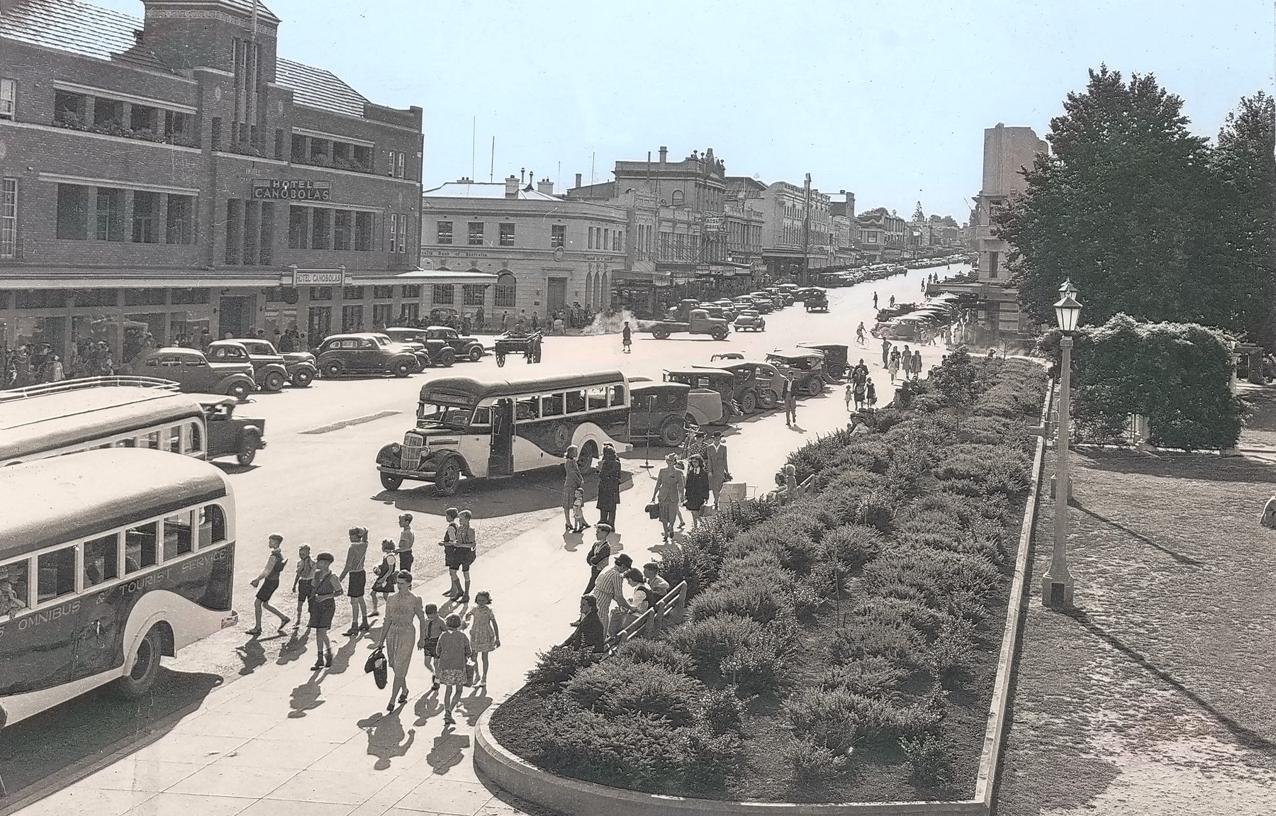 Summer Street, Orange, in the mid-1940s. Buses and parked cars line the wide street, people cross at the median garden, and the Hotel Canobolas stands on the corner.